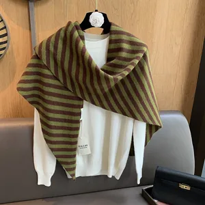 Detail of striped pure wool knitted shawl in brown and olive green on a white knit sweater