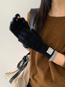 Detail of black fingerless gloves with touchscreen openings and ribbed gray cuffs