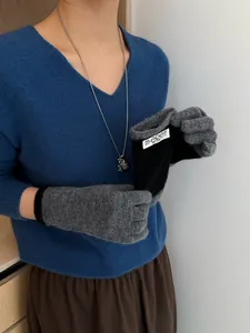 Detail of gray knitted touchscreen gloves with black ribbed cuffs and brand label