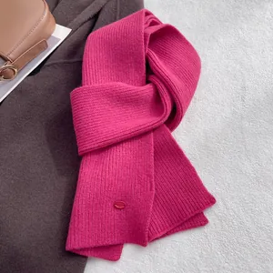 Detail of rose red knit wool scarf with ribbed texture and small oval decorative button