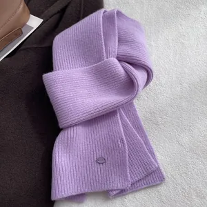 Details der lavendelfarbenen Wollstrickschal-Textur mit lila Metall-Logo-Plakette