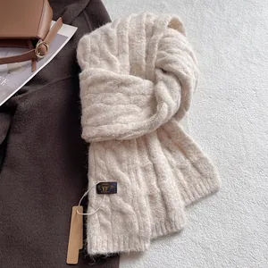 Close-up of cable knit wool scarf texture with brand tag on neutral winter coat background