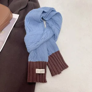 Detail of blue and brown cable-knit scarf with decorative label on soft carpet