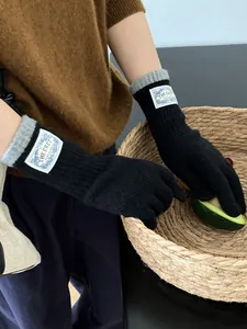 Detail of knit gloves showing black body and grey ribbed cuffs with rectangular label