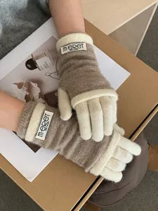 Detail shot of oatmeal and white layered knit gloves with brand woven label on the wrist