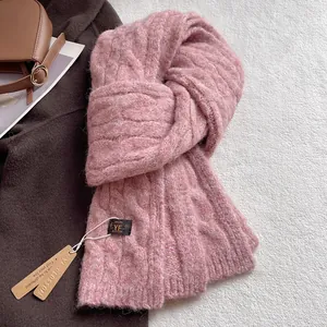 Detail shot of pink wool blend scarf with cable knit texture and branded woven label