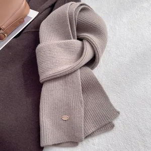 Close-up of light brown ribbed knit wool scarf with elegant oval metal charm detail