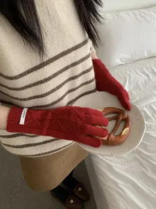 Detailed shot of red wool knit gloves with diamond cable patterns and touchscreen function