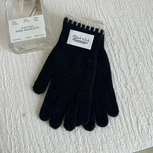 Detail of black knit thermal gloves featuring stylish contrast wavy cuffs and a woven label
