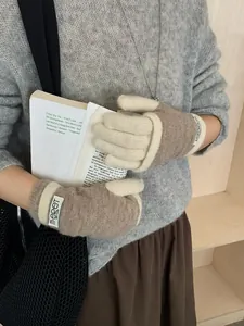 Detail of knit gloves with camel and cream contrast design and brand label