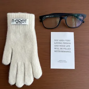 Detailed texture of warm cream knit gloves with touch screen tips and brand label