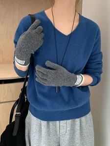 Close-up of dark grey knitted gloves featuring white contrast ribbed cuffs and woven label