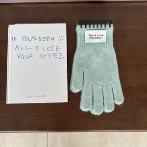 Close-up of mint green knitted glove featuring contrast edging and a white fabric label