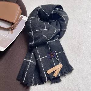 Detail of soft black and white plaid cashmere-like scarf with fringe on plush carpet