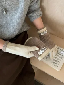Detailed texture of knit fingerless gloves in cream and coffee with a classic cloth label