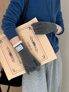 Detail of dark grey knit gloves with white ribbed cuffs and woven brand label