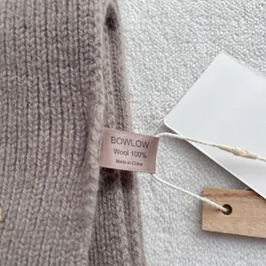 Detailed view of 100% wool beige scarf showing fine ribbed texture and fabric label