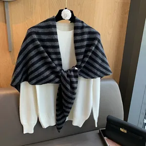 Detail of striped 100% pure wool knitted shawl over a cream crewneck sweater