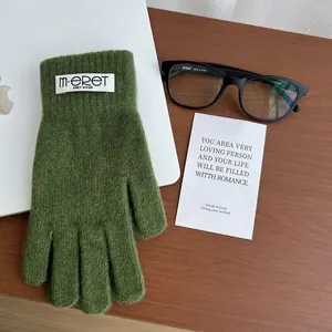 Detail of green knitted thermal glove with woven label on wooden table setting