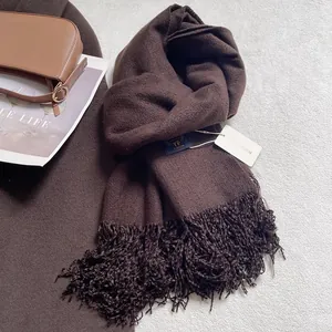 Dettaglio di sciarpa marrone scuro con nappe ed etichetta su un set accogliente
