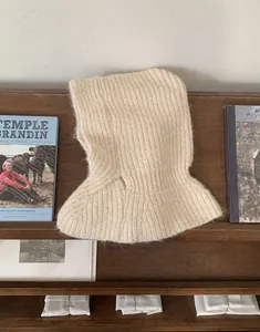Nahaufnahme einer beige gestrickten Balaclava mit grobem Rippenmuster auf Holz