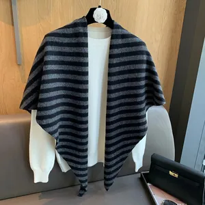Detail of grey striped wool knit shawl styled over a cream sweater for a layered look