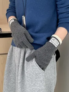 Detailed close-up of dark grey knitted gloves with contrast ribbed cuffs and woven brand tag