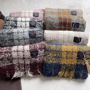 Thick plaid and solid scarves with long fringes in multiple colors on a plush background
