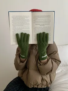 Close-up of moss green cable knit merino wool gloves with vintage woven wrist labels