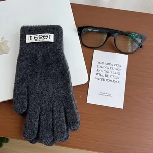 Detail of dark grey knit gloves with fluffy texture and brand label on wooden desk
