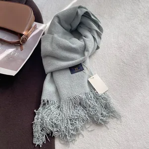 Dettaglio della sciarpa invernale grigio-ciano chiaro con nappe spesse e maglia morbida