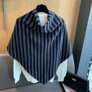 Detail of striped wool knit shawl draped over a white sweater on a wooden hanger