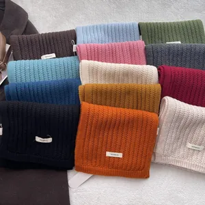 Dettaglio ravvicinato di sciarpe in lana 100% in vari colori con trama a maglia a coste