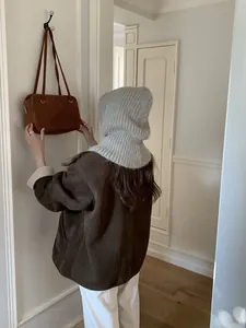 Detail der grauen Strick-Balaclava kombiniert mit brauner Wildlederjacke und Tasche