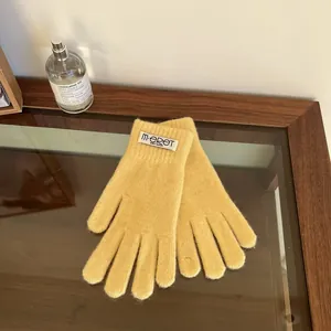 Detail of yellow knit gloves with brand label on a wooden table with soft lighting