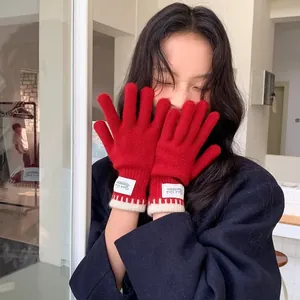 Women's warm red knitted gloves with white label and ribbed cuffs for winter