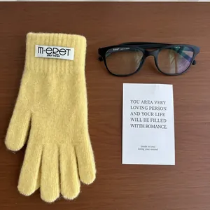 Detailed texture of ginger yellow knitted gloves with woven label on wooden background