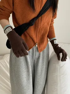 Close-up of winter knit color-block gloves with warm blue ribbed cuffs and brand patch