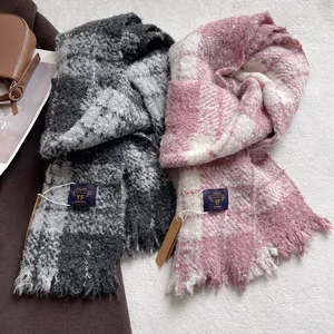 Detailed texture of thick grey plaid boucle scarf with fringes and woven brand label