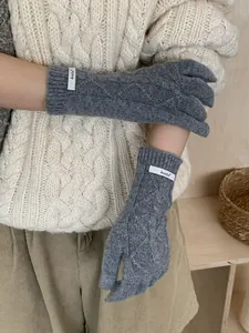 Detail of grey merino wool knit gloves with diamond cable pattern and brand label