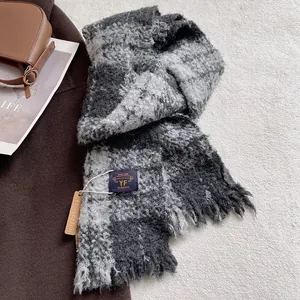Detailed texture of thick grey plaid scarf with soft fringes and premium woven label