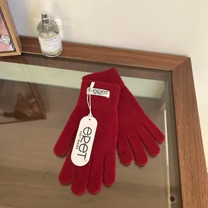 Detail of dark red knit glove texture with woven m.eret label and brand hangtag