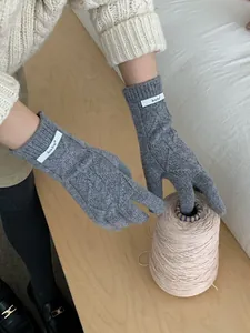 Macro shot of grey cable-knit wool gloves with brand label in a cozy winter scene