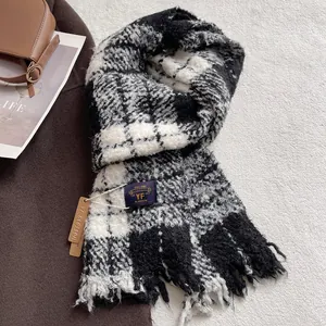 Close-up of thick plaid scarf texture with tassel edges and YF BLOSSOM brand label