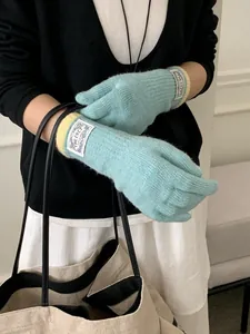 Detail of light blue knit gloves with a yellow ribbed cuff and white brand tag