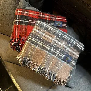 Détail d'écharpes à carreaux avec franges et étiquette de marque sur tissu gris