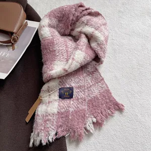 Detail showing soft pink and white plaid scarf texture with brand tag and fringe