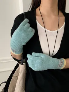 Detailed knit texture of mint green gloves with pale yellow ribbed cuff and label