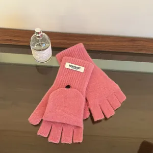 Detail of pink wool knit gloves featuring convertible fingerless flap and black button