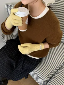 Close-up of yellow merino wool knitted gloves featuring a classic cable knit pattern detail